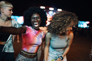 Enthusiastic friends enjoying live music at night festival
