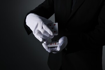 Illusionist shuffling playing cards on black background, closeup