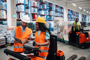 Warehouse workers using digital tablet and driving forklift in logistics center