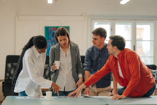 Marketing team analyzing charts and discussing strategy in modern office - Powered by Adobe