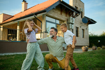 Grandfather playing with grandchildren in backyard of house