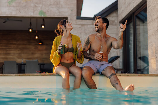 Happy couple laughing and pointing while relaxing by the pool