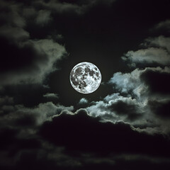 Bright full moon illuminating swirling dark clouds at night in a moody atmospheric sky