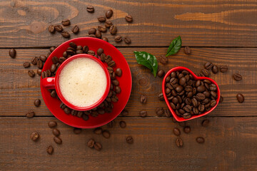 Cup of coffee with coffee beans and leaves on wooden background,top view