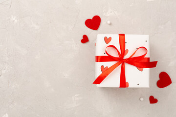 Gift boxes with red hearts on concrete background, top view
