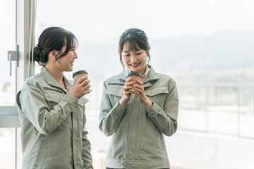 工場・中小企業で休憩・会話するエンジニア・作業員の女性従業員
