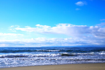 遠くに佐渡島を望む白波寄せる冬晴れの日本海