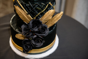 Incredible black and gold wedding cake with black roses and gold feathers