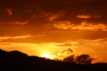 Obraz premium Golden hour sunset over a silhouetted mountain