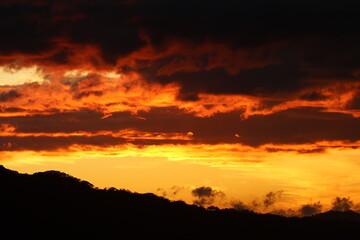 Fiery sunset over silhouetted mountains and trees