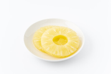 お皿に載せたパイナップルの輪切りのシロップ漬け（缶詰）