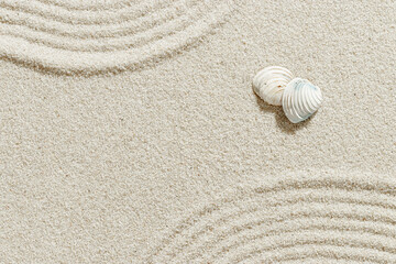 Close-up of white seashells on textured light beige sand with Japanese Zen Garden lines, summer and...