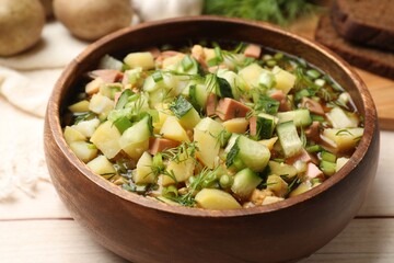 Delicious okroshka soup with kvass and ingredients on white wooden table, closeup