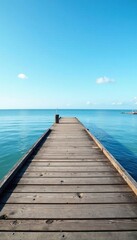 Fototapeta premium Wooden pier stretches over calm waters beneath blue sky, calm, sky, clear