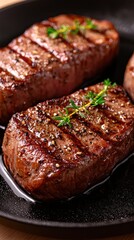 Juicy grilled steaks garnished with herbs, served on a black plate.