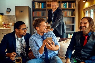 Young group of people using a smart phone while watching a sports game in the living room