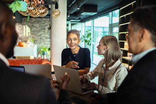 Business professionals discussing document with a colleague in modern office