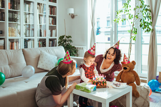 Lesbian couple celebrating daughters birthday party at home with cake