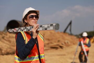 Land surveyors on the construction site. Senior female civil engineers carry out level ruler...