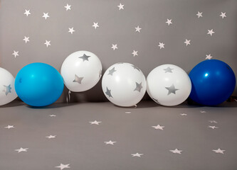 Set fotográfico digital con ciclorama gris adornado con recorte de estrellas, con globos blancos adornados con estrellas y globos azules adornando