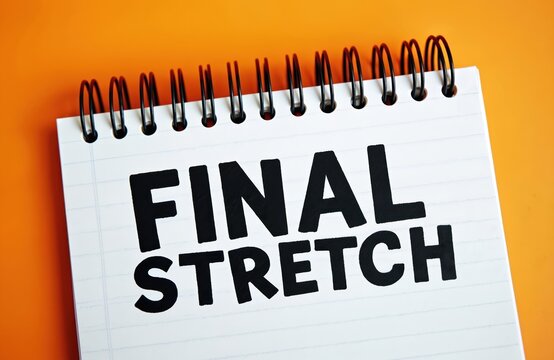 Notepad with Final Stretch message. Concept of finishing, closing or cessation. Completion stage metaphor for business projects. End of road or competition. Almost done. Orange background.