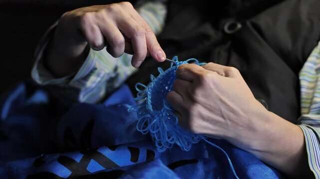 Close-up. Woman's hands crocheting a product made of blue polypropylene nylon plastic twine. Hobby-knitting and handmade crafts for relaxation and mental health