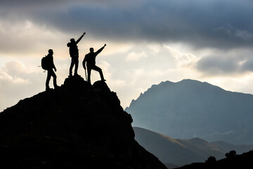 People silhouetted on a mountain top at sunset enjoying the view