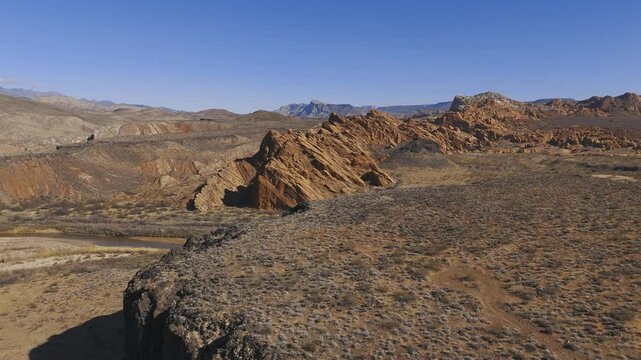 VIRGIN RIVER GORGE, UTAH, USA - February 07, 2025: Flying over a black basalt cliff rim toward an angled sandstone up thrust geological formation in the Virgin River gorge near the town of Hurricane