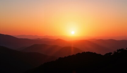 Glowing horizon over mountainous landscape at sunset with soft light illuminating the hills
