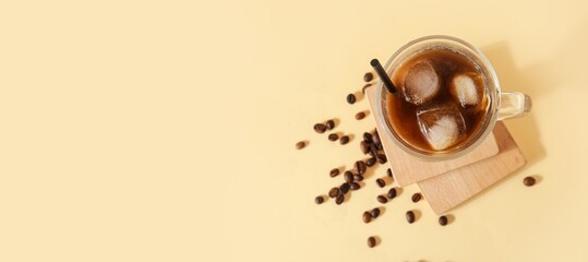 Glass cup of ice coffee on yellow background with space for text, top view