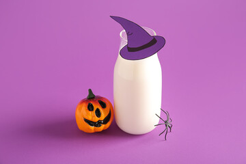 Bottle of milk, hat made of paper, pumpkin and spider for Halloween on purple background