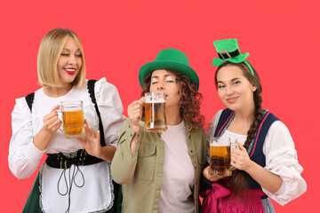 Portrait of happy women with beer celebrating St. Patrick's Day on red background
