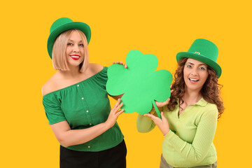 Happy women with paper clover on yellow background. St. Patrick's Day