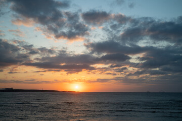 A stunning sunset over Tamsui Beach with vibrant pink and purple hues in the sky. The calm sea reflects the colorful sky, creating a serene atmosphere. Tamsui, Taiwan.