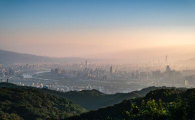 A breathtaking view of Taipei cityscape from Dajian Mountain, in the early spring morning. The golden sunlight bathes the buildings. The sky is a canvas of pink and orange hues. Xizhi, Taiwan.