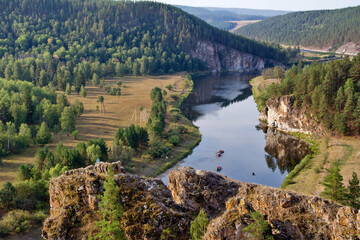 Obraz premium picturesque view of the Belaya River, the South Ural taiga, tourists rafting from the Insebika cliff on a summer day