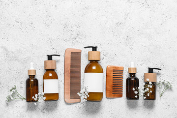 Composition with bottles of shampoo, wooden combs and gypsophila flowers on white background