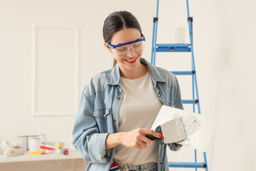Young woman with putty knives in room
