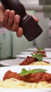 Chef seasoning spaghetti dinners with black pepper