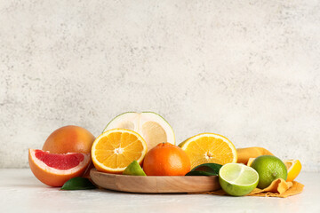 Wooden tray with tasty citrus fruits on white background