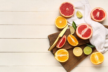 Wooden cutting boards with tasty citrus fruits on white wooden background