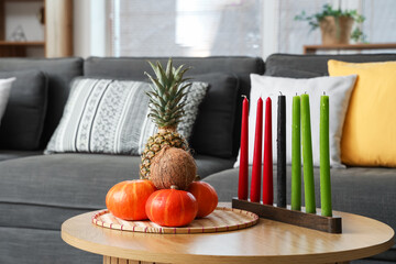 Candles and fruits for Kwanzaa celebration on table in living room, closeup
