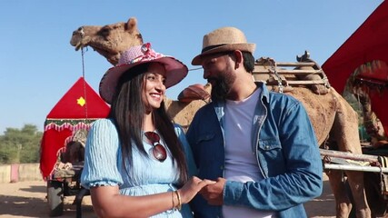 Young indian romantic couple wearing hat holding hands together standing outdoor enjoying holidays in rajasthan, Summer vacation, tourist Husband wife love and bonding.