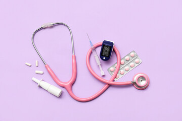 Composition with pulse oximeter, stethoscope, syringe and medicines on lilac background
