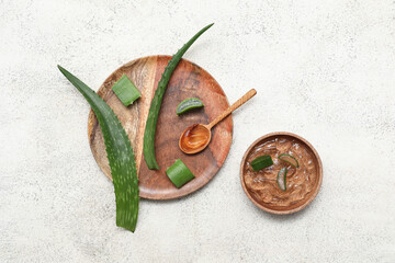 Wooden tray, bowl with fresh aloe gel and leaves on white grunge background