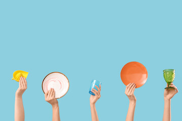 Female hands with plates, glasses and squeezer on blue background