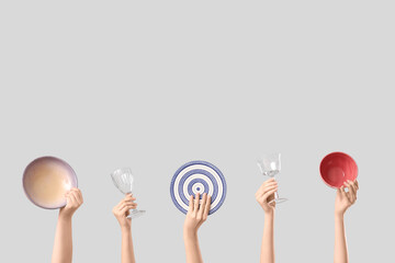Female hands with plate, bowls and glasses on white background