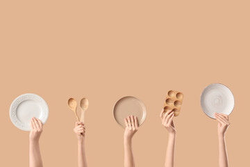 Female hands with plates, wooden egg holder and spoons on beige background