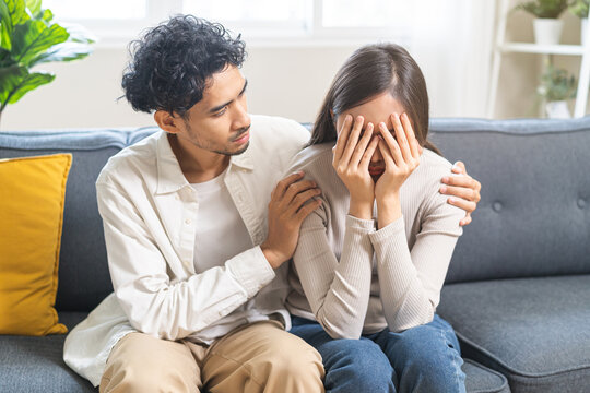 Anxiety depress, grief asian young couple comfort discuss concern encourage empathy and support, worry about problem mental health about relationship after marriage, upset wowan sad on sofa at home.