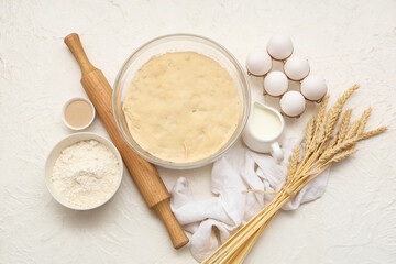 Composition with wooden rolling pin, dough and ingredients on white background